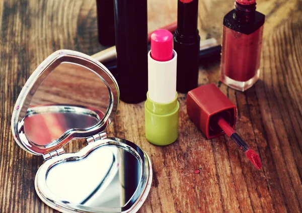 Espelho de bolso bonito em forma de coração com batom rosa e outros cosméticos na mesa de madeira — Fotografia de Stock