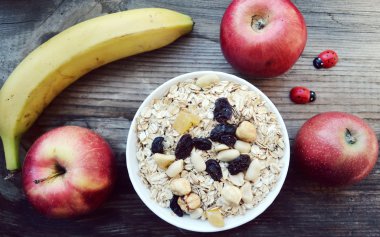 Çiğ yulaf gevreği ile fındık ve ahşap masa üzerinde beyaz kase kuru üzüm