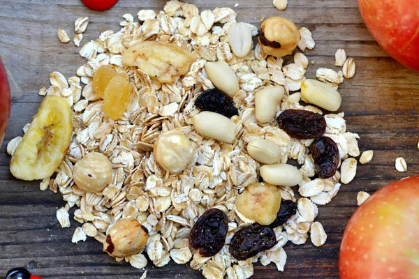 Raw oatmeal flakes with nuts and raisins on wooden table — Stock Photo, Image