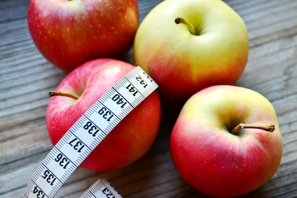 Concepto de dieta con manzanas rojas y amarillas y cinta métrica blanca en mesa de madera — Foto de Stock