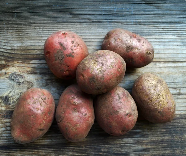 Dirty raw potatoes on wooden table — Stock Photo, Image