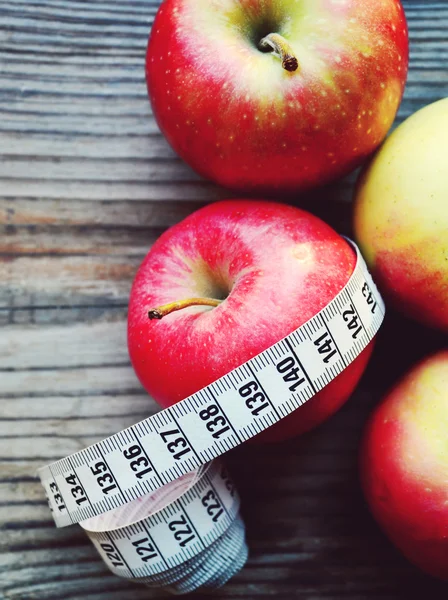 Concepto de dieta con manzanas rojas y amarillas y cinta métrica blanca en mesa de madera —  Fotos de Stock