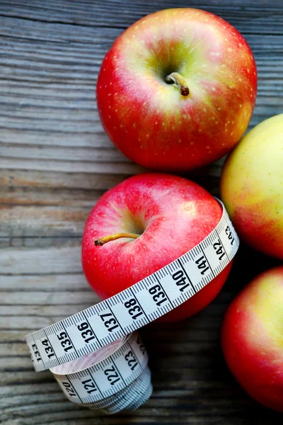 Concepto de dieta con manzanas rojas y amarillas y cinta métrica blanca en mesa de madera —  Fotos de Stock