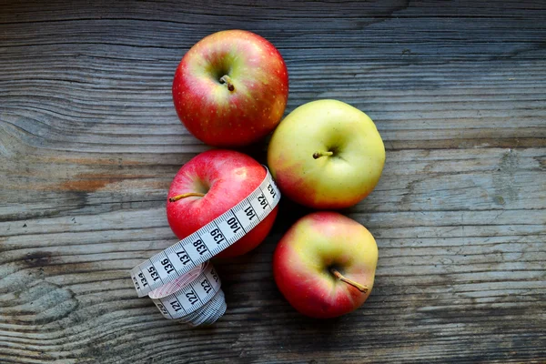 Concepto de dieta con manzanas rojas y amarillas y cinta métrica blanca en mesa de madera —  Fotos de Stock