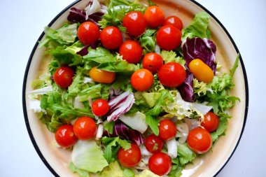 Tasty vegetarian salad with red and yellow cherry tomatoes, arugula, cabbage and lettuce clipart