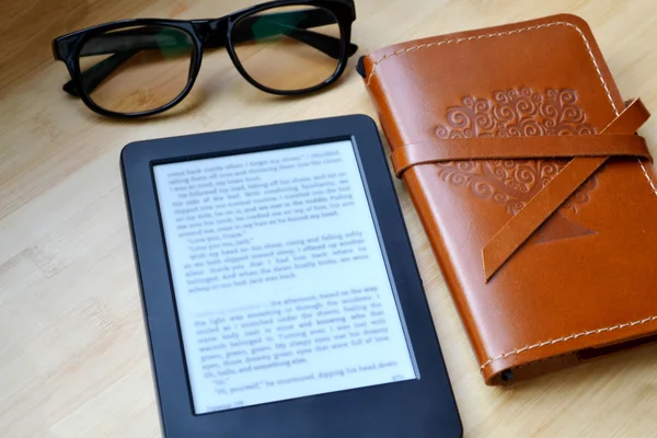 Cereader preto com óculos de leitura e um velho caderno em capa de couro na mesa de madeira — Fotografia de Stock