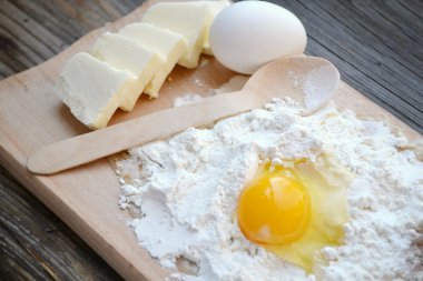 yumurta, tereyağı ve tahta kaşık yemek kartı üzerindeki beyaz un
