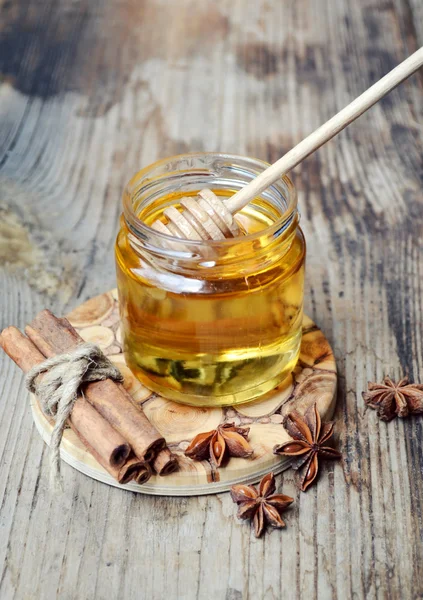 Golden honey with honeystick. cinnamon and anise stars on wooden table — Stock Photo, Image