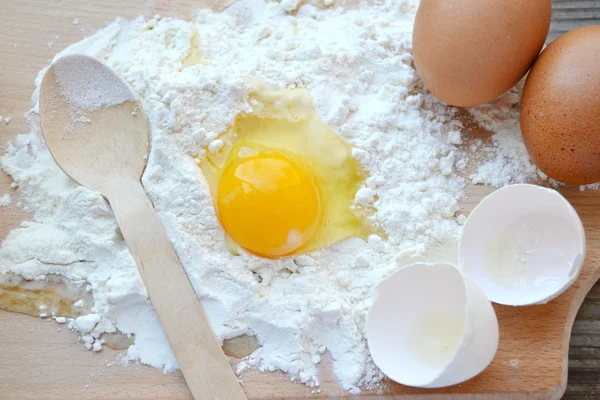 White flour with eggs, butter and wooden spoon on a cooking board — Stock Photo, Image