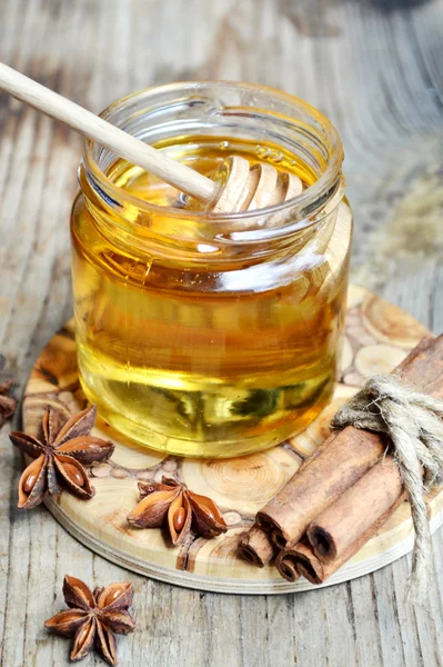 Golden honey with honeystick. cinnamon and anise stars on wooden table — Stock Photo, Image