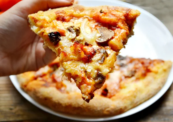 チーズ、キノコとトマトのピザのスライスを持っている手 — ストック写真