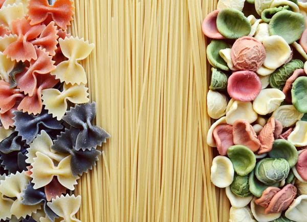 A különböző típusú színes olasz tészták meg fából készült asztal — Stock Fotó