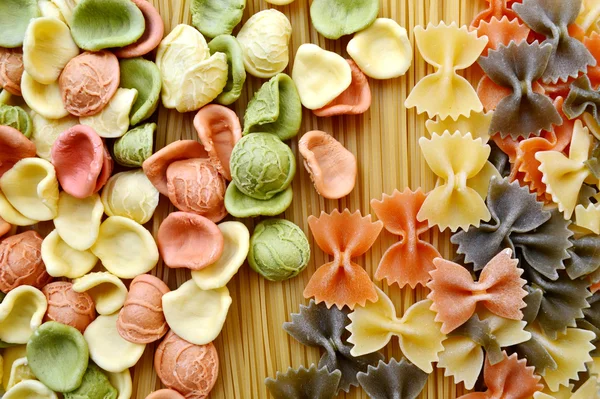 A különböző típusú színes olasz tészták meg fából készült asztal — Stock Fotó