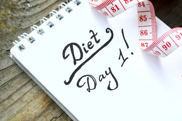 Conceito de dieta com um caderno e fita métrica vermelha na mesa de madeira — Fotografia de Stock