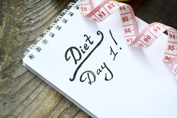 Diet concept with a notebook and red measuring tape on wooden table — Stock Photo, Image