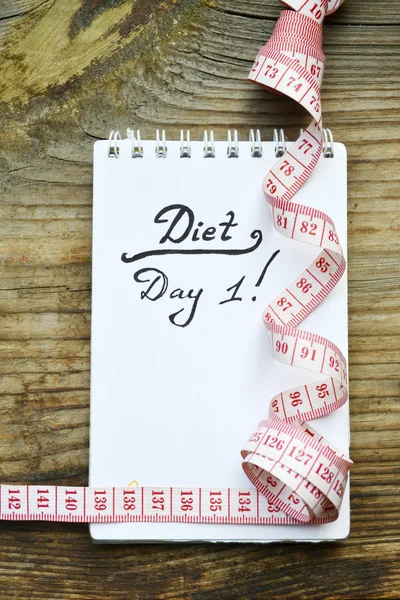 Conceito de dieta com um caderno e fita métrica vermelha na mesa de madeira — Fotografia de Stock