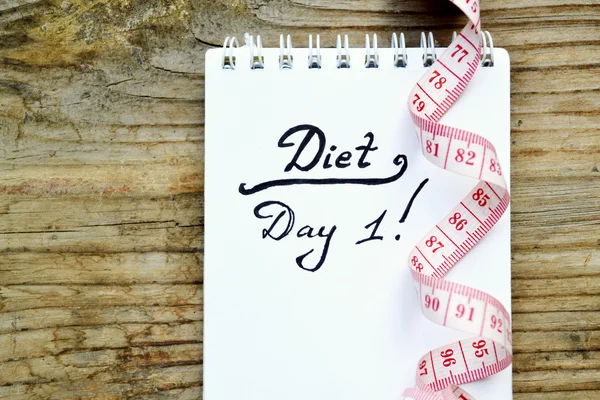 Conceito de dieta com um caderno e fita métrica vermelha na mesa de madeira — Fotografia de Stock