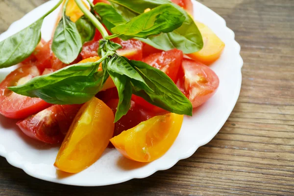 Tomates jaunes et rouges dans une assiette au basilic frais — Photo