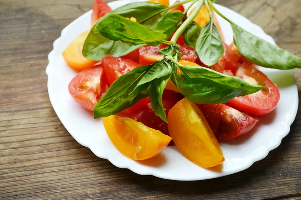 Tomates jaunes et rouges dans une assiette au basilic frais — Photo