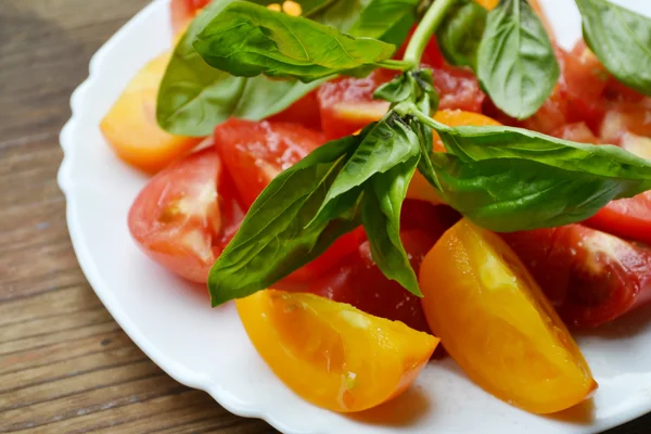 Tomates jaunes et rouges dans une assiette au basilic frais — Photo
