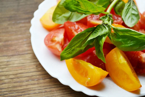 Tomates jaunes et rouges dans une assiette au basilic frais — Photo