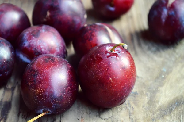 Bowl with plums on wooden table — Stock Photo, Image