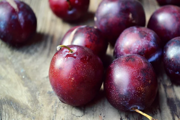 Bowl with plums on wooden table — Stock Photo, Image