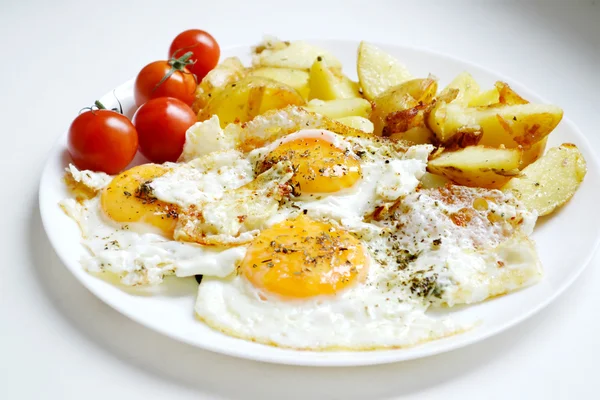 Grande assiette ronde pleine d "œufs frits, de frites et de tomates cerises - un petit déjeuner continental traditionnel — Photo