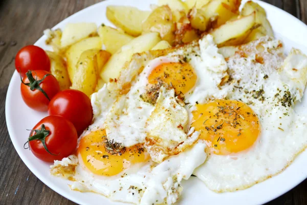 Gran plato redondo lleno de huevos fritos, papas fritas y tomates cherry - un desayuno continental tradicional — Foto de Stock