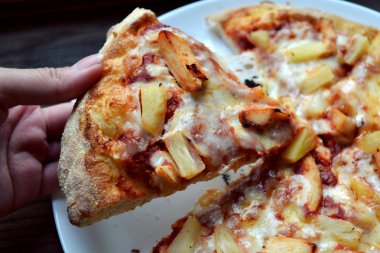 Ananas ve tavuk Hawai pizza bir dilim tutan el