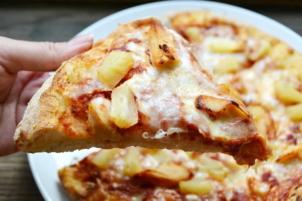 Hand met een plak van Hawaiian pizza met ananas en kip — Stockfoto