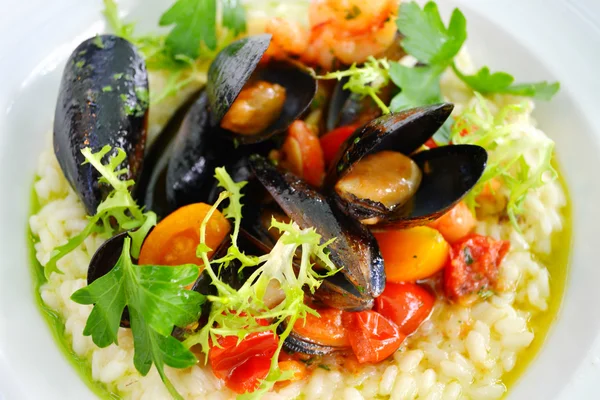 Leckeres Risotto mit Muscheln und Garnelen auf weißem Teller im Restaurant Stockbild