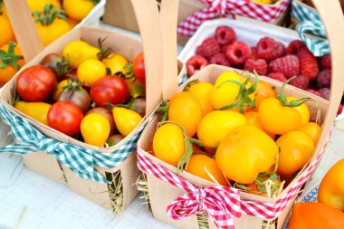 Küçük kırmızı, kahverengi ve sarı organik kiraz domates kovalar bir semt pazarı üzerinde farklı türde