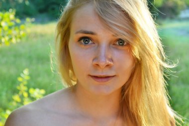 uzağa bakarak ve hafifçe gülümseyerek uzun saçlı genç güzel sarışın kadın