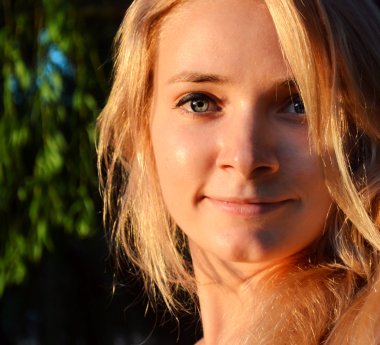 doğrudan bakarak ve hafifçe gülümseyerek uzun saçlı genç güzel sarışın kadın