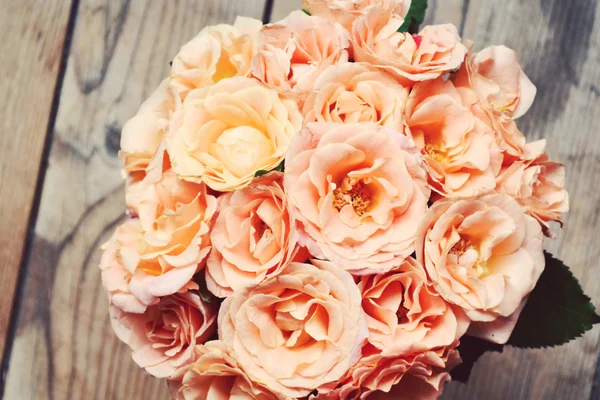 Beautiful wedding bouquet of apricot roses on wooden background — Stock Photo, Image