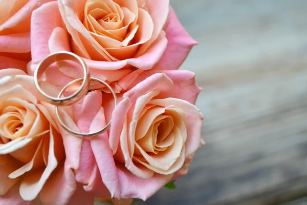 Dois anéis dourados de noivado em um lindo buquê de casamento de rosas rosa — Fotografia de Stock