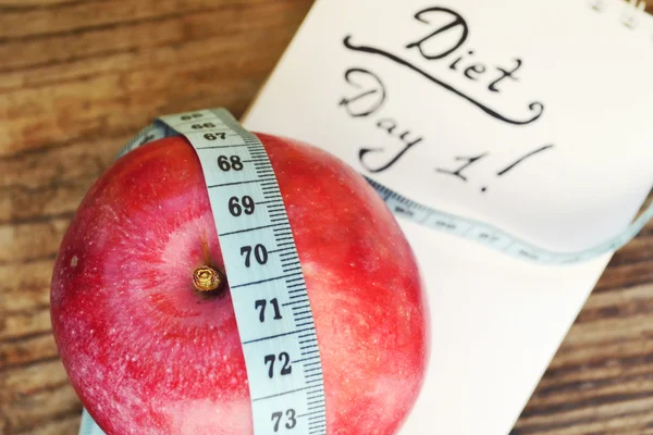 Conceito de dieta com maçã vermelha, um notebook e fita métrica azul na mesa de madeira — Fotografia de Stock