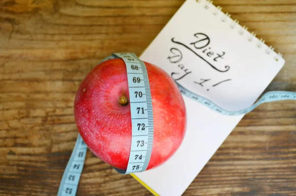 Pojęcie diety z czerwone jabłko, notatnik i niebieska taśma miernicza na drewnianym stole — Zdjęcie stockowe