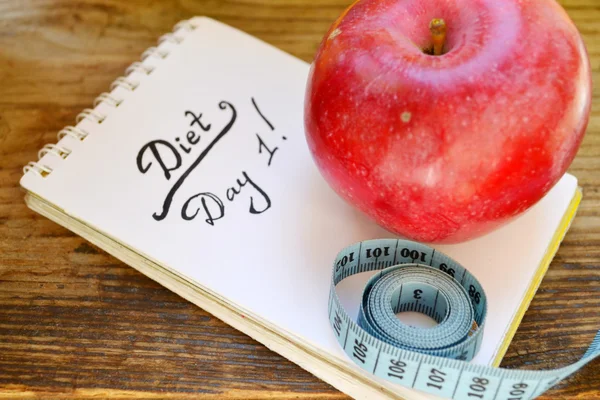 Dieta concetto con mela rossa, un notebook e nastro di misurazione blu su tavolo di legno — Foto Stock