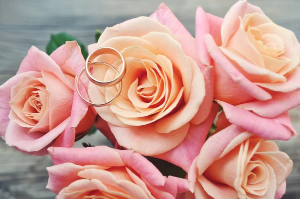 Два обручальных золотых кольца на красивом свадебном букете розовых роз — стоковое фото
