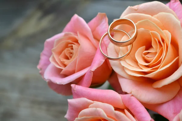 Dois anéis dourados de noivado em um lindo buquê de casamento de rosas rosa — Fotografia de Stock