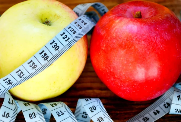 Koncept stravy s červených a žlutých jablek a modré měřící páska na dřevěný stůl — Stock fotografie