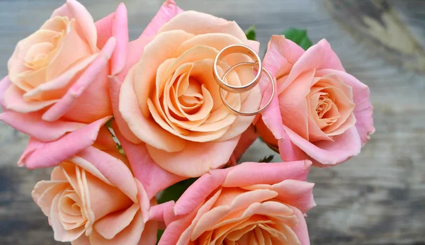 Dois anéis dourados de noivado em um lindo buquê de casamento de rosas rosa — Fotografia de Stock