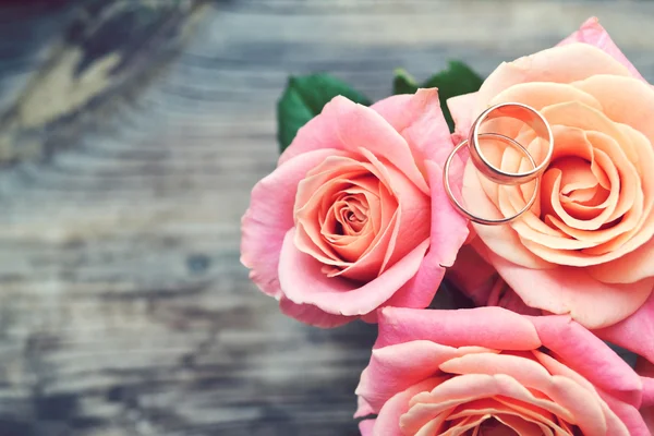 Zwei goldene Verlobungsringe an einem wunderschönen Brautstrauß aus rosa Rosen — Stockfoto