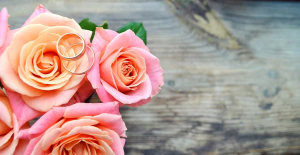 Due anelli d'oro di fidanzamento su un bellissimo bouquet da sposa di rose rosa — Foto Stock