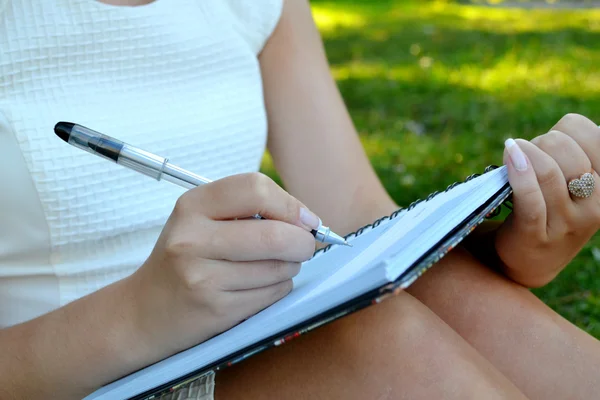Woman with beautiful hands writing in her diary — Stock Photo, Image