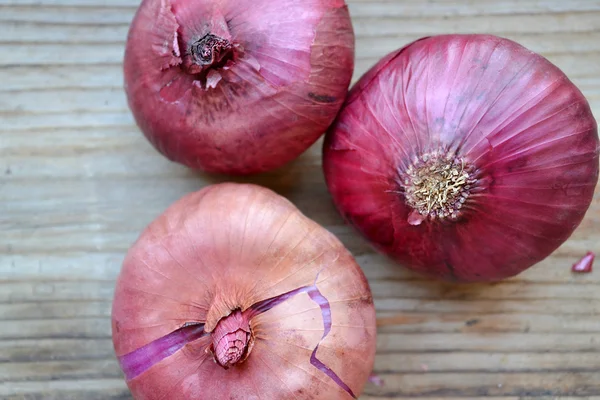 Oignons rouges entiers sur table en bois — Photo