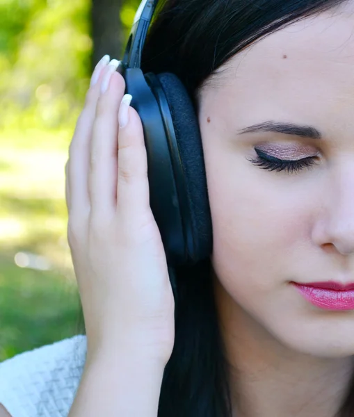 Beautiful brunette woman in big headphones listening to the music — Stock Photo, Image