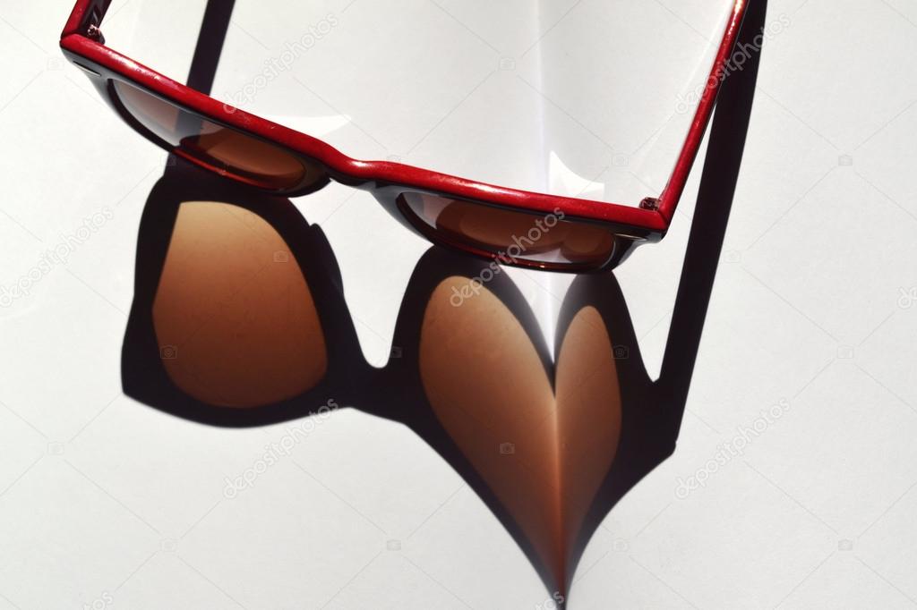 Red vintage sunglasses on a notebook giving the shadow on a heart